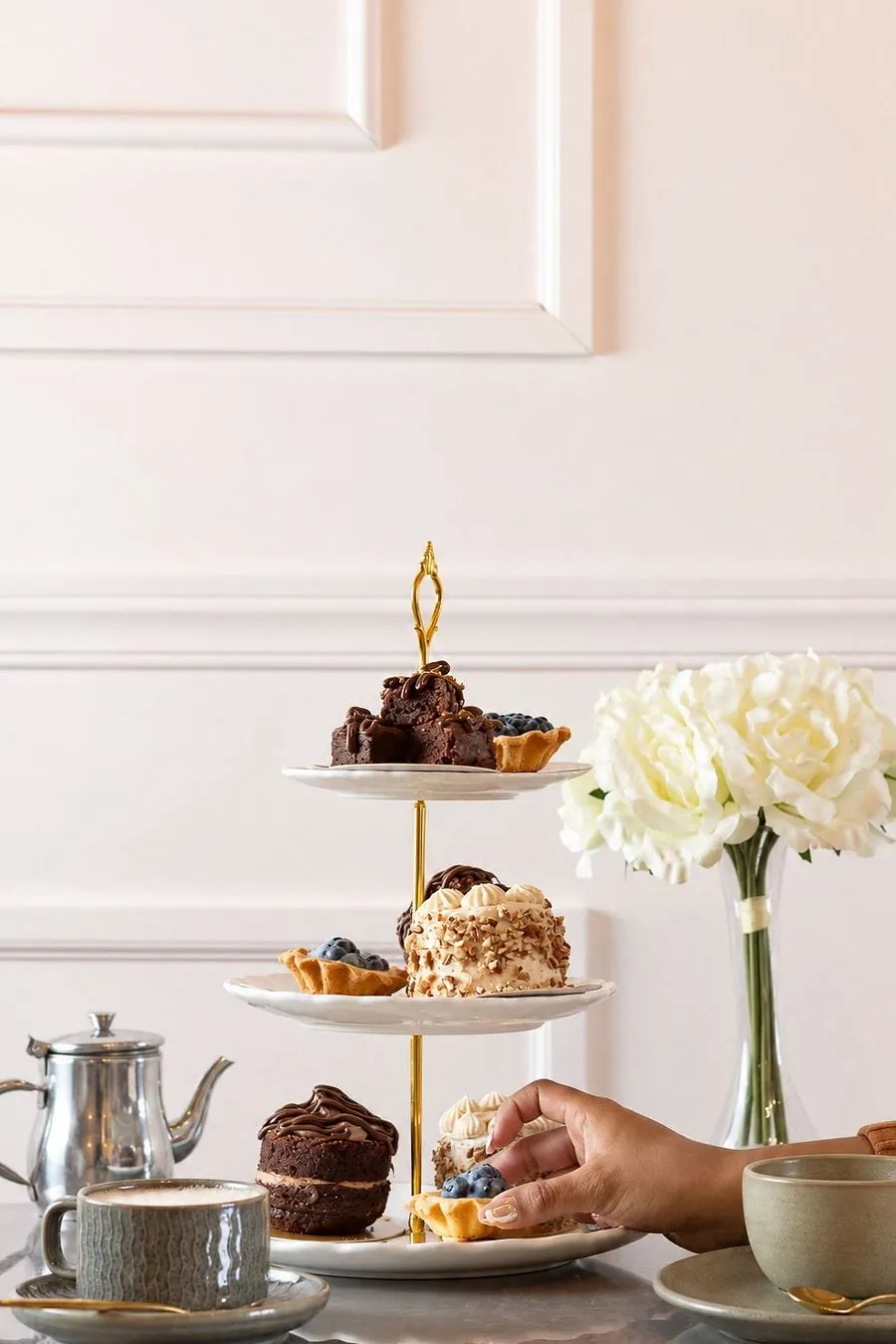 Mesa con torre de postres, tetera y capuchinos